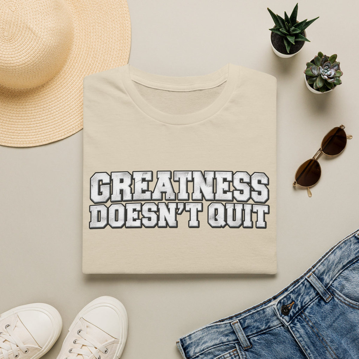 SatsandStripes.com Greatness Doesn’t Quit Softstyle® T-Shirt – Motivational Graphic Tee, Inspirational Shirt, Positive Mindset Gift for Men & Women Sand Folded